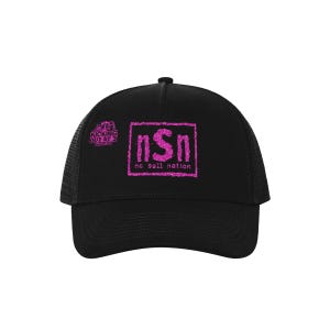 Puede incluir: Una gorra de camionero negra con un gráfico de purpurina rosa en el panel frontal. El diseño incluye un borde rectangular que rodea las letras nSn y el texto no sell nation. Un logotipo más pequeño dice KICKING OUT AT 2 PODCAST.