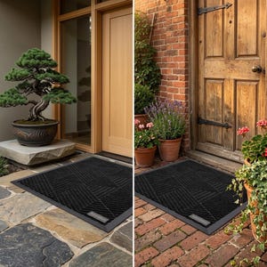 May include: A rectangular black doormat featuring a geometric pattern of raised diagonal lines and a small rectangular label in the corner. The mat is shown placed on stone and brick surfaces in front of wooden doors with potted plants nearby.