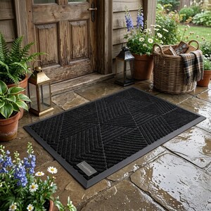 May include: A rectangular black doormat featuring a textured geometric pattern of raised lines and triangles. The mat has a solid black border and a small rectangular label in the bottom left corner with the text Kangabound printed in white.