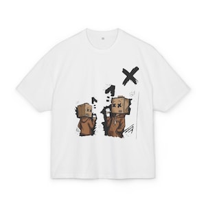 Può includere: Una t-shirt bianca a maniche corte con una stampa grafica di due figure che indossano scatole di cartone marroni sulla testa. Le figure indossano felpe con cappuccio marroni e tengono in mano bicchieri bianchi, con accenti a pennellata nera.