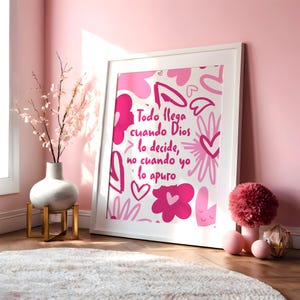 Puede incluir: Un cuadro con marco blanco que presenta un fondo rosa y blanco con formas abstractas de corazones y flores. El texto en el centro dice: Todo llega cuando Dios lo decide, no cuando yo lo apuro, escrito en una fuente cursiva rosa oscuro.
