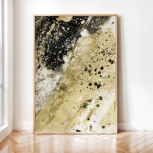 Puede incluir: Una impresión de arte mural rectangular en un marco de madera clara con una composición abstracta de pintura negra, blanca y dorada. El diseño muestra una mezcla texturizada de lavados oscuros, puntos negros salpicados y pigmento dorado.