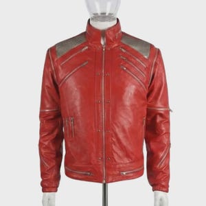 May include: A bright red leather jacket featuring a high collar, silver-toned metal zips across the chest and sleeves, and metallic silver textured panels on the shoulders. The front closure includes a central zip and vertical rows of metal studs.