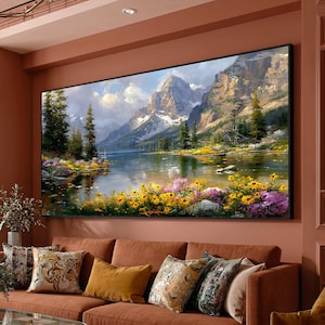 May include: A rectangular landscape painting featuring a snow-capped mountain range rising above a calm lake. The foreground is filled with vibrant yellow and purple wildflowers, while tall evergreen trees stand along the shoreline under a cloudy sky.