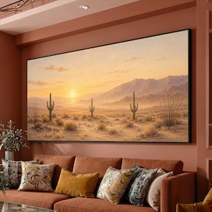 May include: A large rectangular wall art print featuring a desert landscape at sunset. The scene displays a vast sandy terrain with three prominent saguaro cacti, sparse desert vegetation, and distant mountains under a warm golden sky.