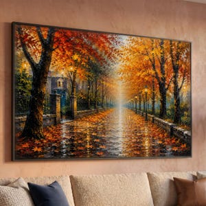 Puede incluir: Un cuadro rectangular de pared con una pintura al óleo de un camino arbolado en otoño. La escena muestra follaje naranja y amarillo vibrante, un sendero húmedo y reflectante cubierto de hojas caídas y farolas de hierro negro a los lados.