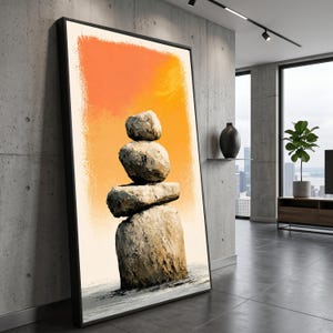 Op de afbeelding: Een ingelijst verticaal kunstwerk aan de muur met een stapel van vier gestructureerde grijze stenen in balans tegen een levendige oranje en gele gradiëntachtergrond. De onderkant van het kunstwerk toont een grijs, gestructureerd oppervlak.