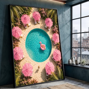 Puede incluir: Una impresión de arte mural enmarcada que muestra una vista aérea de una piscina circular turquesa rodeada de sombrillas rosas y tumbonas. Una persona flota en un flotador de flamenco rosa en el centro del agua, con palmeras cerca.