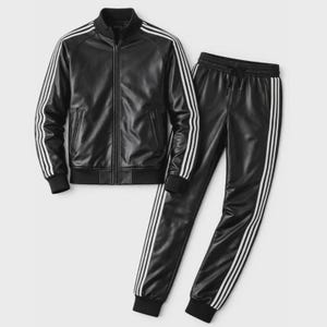 May include: A black faux leather tracksuit consisting of a zip-up jacket and matching joggers. The jacket features a stand-up collar, ribbed cuffs, and three white stripes running down each sleeve. The joggers have an elastic waistband and white stripes.