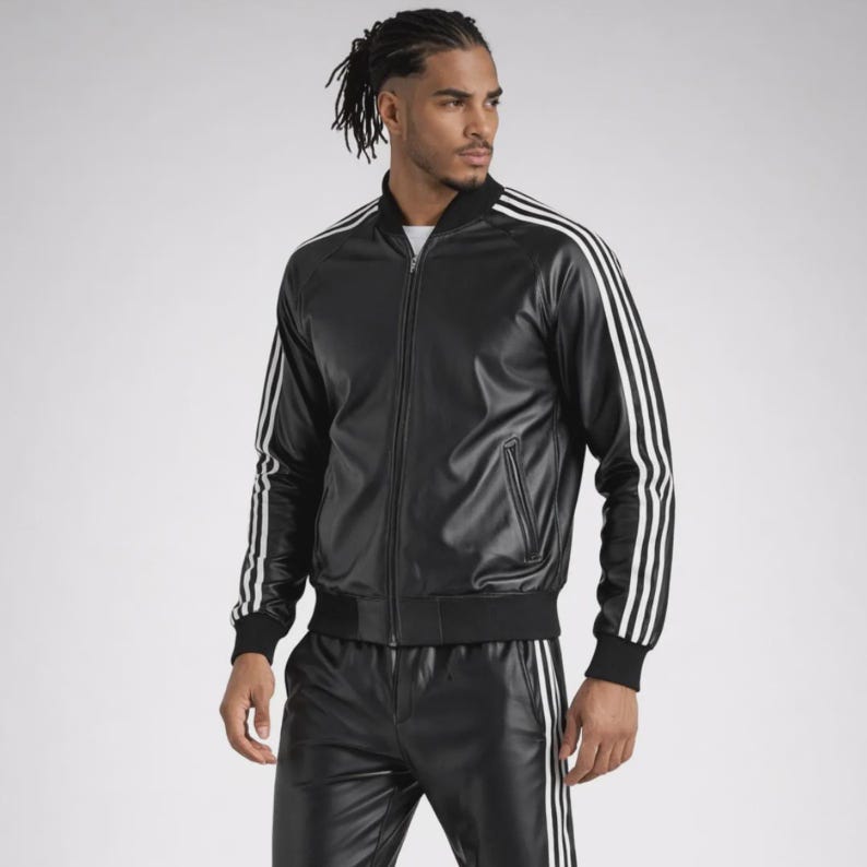 May include: A black faux leather track jacket featuring a full-length front zipper, a ribbed collar, and three white stripes running down the length of each sleeve. The jacket includes two zippered side pockets and ribbed cuffs at the wrists.