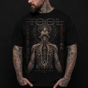Puede incluir: Una camiseta negra de manga corta con la palabra TOOL en letras estilizadas en la parte superior. El gráfico muestra un torso humano anatómico con líneas intrincadas, patrones geométricos y el texto DESCEND WITHIN en la parte inferior.