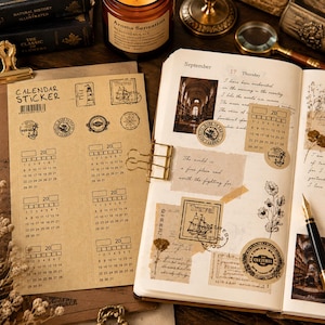 Puede incluir: Una hoja de papel kraft con pegatinas de calendario y sellos de viaje de estilo vintage, junto a un diario abierto decorado con etiquetas adhesivas, ilustraciones botánicas, notas manuscritas y un clip metálico dorado.