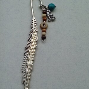 May include: Silver feather bookmark with a wolf charm, turquoise bead, and wooden beads.
