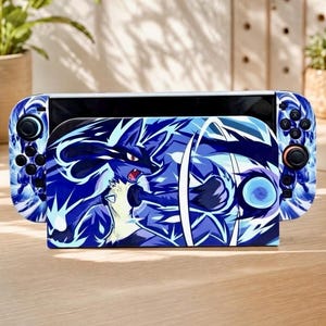 May include: A handheld gaming console featuring a blue and white graphic skin of the character Lucario. The design depicts the character in a dynamic pose with blue energy effects, covering both the central console unit and the side controllers.