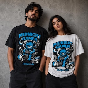 Op de afbeelding: Een zwart T-shirt en een wit T-shirt, elk met een afbeelding van een blauwe kat met een headset die een videogame speelt. De tekst luidt Midnight Gamer en DevSync Labs, vergezeld van illustraties van een klok, een mok en een zak chips.