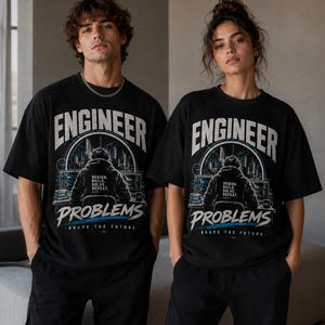 Könnte beinhalten: Ein schwarzes Kurzarm-T-Shirt mit einem Grafikdruck einer Person am Computer, dem Text "ENGINEER PROBLEMS" in großen weißen Buchstaben, "DESIGN, BUILD, SOLVE, REPEAT." und "SHAPE THE FUTURE" im unteren Bereich.