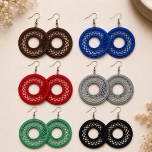 May include: Six pairs of circular drop earrings featuring intricate thread-work patterns. The collection includes brown, blue, red, grey, green, and black colors, each suspended from silver-toned metal hooks with a consistent open-center design.