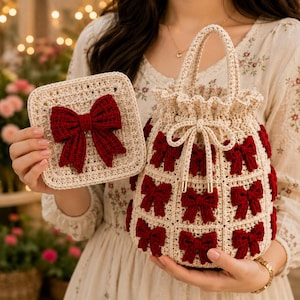 May include: A cream-colored crochet drawstring bag and a matching square coaster, both featuring a grid pattern decorated with small, dark red crocheted bows. The bag has a ruffled top edge and a drawstring closure with gold-toned metal tips.
