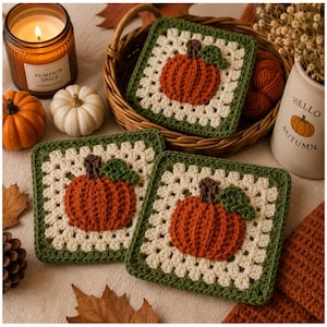 May include: Three square crochet coasters featuring a central orange pumpkin motif with a brown stem and green leaf, surrounded by a cream-colored granny square pattern and a dark green border. The coasters are arranged with two in the foreground.