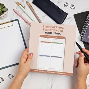May include: A square paper planner sheet with a light pink background featuring the text STOP CARRYING EVERYTHING IN YOUR HEAD and GET IT OUT, CLEAR YOUR MIND, START FRESH. The sheet includes a four-quadrant grid labeled for task organization.