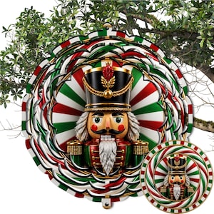 May include: A circular metal wind spinner featuring a central nutcracker figure with a black hat, white beard, and green and red uniform. The background consists of a radiating pattern of red, white, and green stripes. A smaller matching spinner is included.