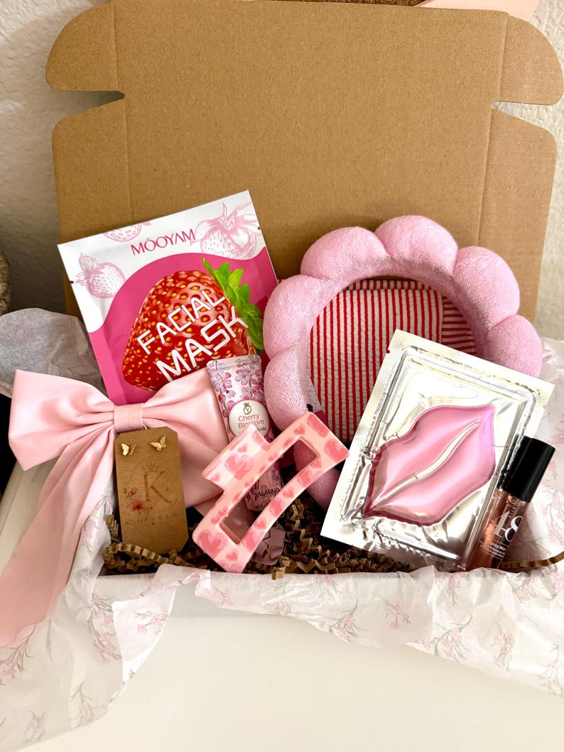 Puede incluir: Una caja de regalo que contiene una mascarilla facial de fresa Mooyam, una diadema rosa festoneada, una mascarilla para labios, una pinza para el cabello rosa con corazones, un lazo rosa claro, un tubo de crema de flor de cerezo y pendientes de mariposa dorados.