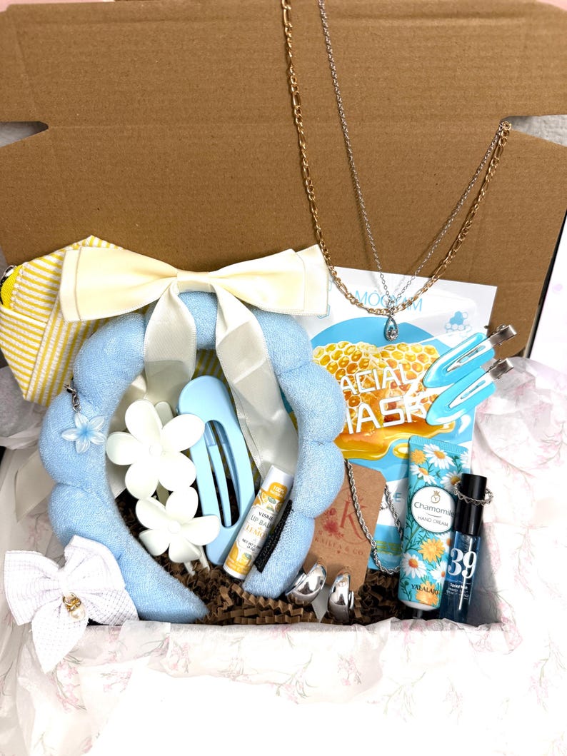 Puede incluir: Una caja de regalo que contiene una diadema de felpa azul claro con un lazo blanco, dos collares en tonos oro y plata, una bolsa a rayas amarillas, dos pinzas para el pelo azul claro, b&aacute;lsamo labial de lim&oacute;n, crema de manos y pendientes.