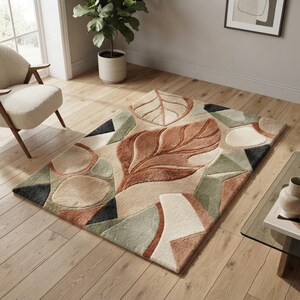 Puede incluir: Una alfombra rectangular con un diseño de mechones que presenta grandes hojas estilizadas y formas geométricas en tonos terracota, verde salvia, crema y negro carbón. La alfombra tiene un pelo texturizado con alturas variables.