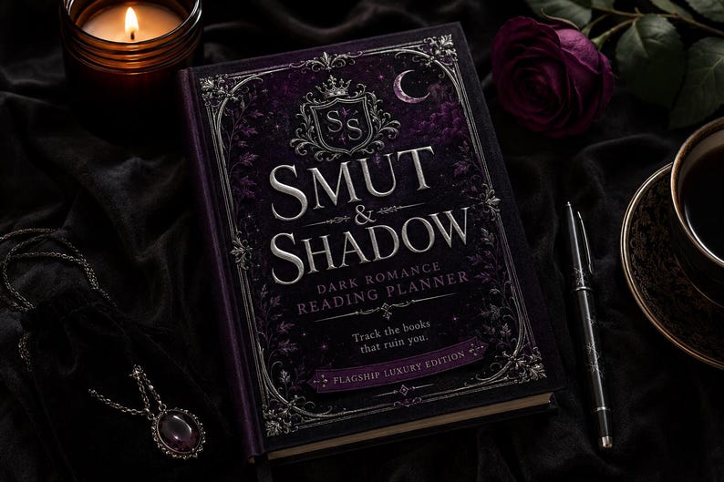 K&ouml;nnte beinhalten: Ein dunkelvioletter Hardcover-Leseplaner mit dem Titel Smut & Shadow Dark Romance Reading Planner, verziert mit silberner Folienpr&auml;gung, einem Kronenemblem und filigranen R&auml;ndern. Der Einband enth&auml;lt den Text Track the books that ruin you und Flagship Luxury Edition.