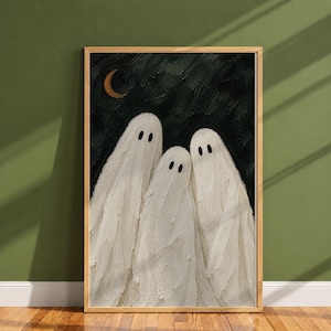May include: A framed wall art print featuring three white ghosts with black oval eyes against a dark, textured black background. A small, golden crescent moon is positioned in the upper left corner. The artwork has a thick, impasto paint texture.