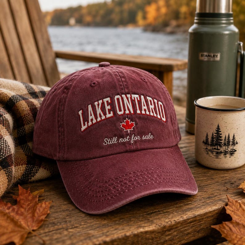 May include: A maroon baseball cap featuring the embroidered white text LAKE ONTARIO in an arched font, a small red maple leaf icon, and the cursive white text Still not for sale. The cap has a structured crown and a curved brim with stitching.