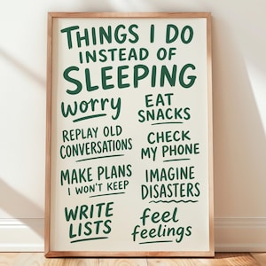 May include: A rectangular wall art print in a light wood frame featuring dark green text on a cream background. The text reads: Things I do instead of sleeping: worry, eat snacks, replay old conversations, check my phone, make plans I won't keep, imagine disasters, write lists, feel feelings.