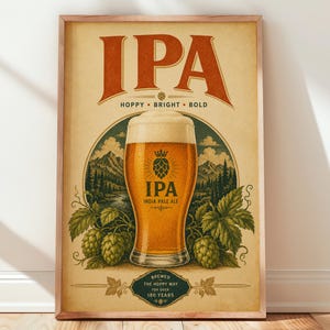 Könnte beinhalten: Ein gerahmtes Poster mit einem Glas goldenem Bier und einer dicken weißen Schaumkrone. Der Text lautet IPA, HOPPY, BRIGHT, BOLD, INDIA PALE ALE und BREWED THE HOPPY WAY FOR OVER 180 YEARS. Der Hintergrund zeigt Berge, Bäume und grüne Hopfendolden.