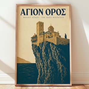 May include: A framed vertical poster featuring a stone monastery perched on a dark blue cliff above the sea. The text reads AGION OROS and MOUNT ATHOS THE HOLY MOUNTAIN in dark blue letters against a light beige background with a single figure.