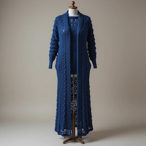 Può includere: Un lungo cardigan blu intenso aperto sul davanti, caratterizzato da un motivo a trecce lavorato a maglia su tutta la superficie. Il capo presenta maniche lunghe, un ampio collo a scialle e un orlo dritto che arriva al polpaccio, su un manichino.