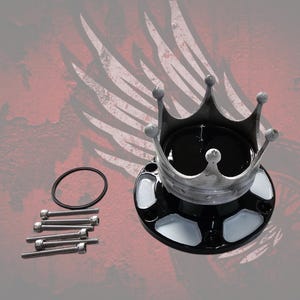 Puede incluir: Un tapacubos en forma de corona de color negro y plata con una parte superior negra brillante, una estructura de corona de plata metálica y una base negra con detalles blancos. Incluye cinco pernos de metal plateado y una junta tórica negra.