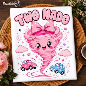 Op de afbeelding: Een wit stoffen oppervlak met een roze cartoon-tornadofiguur met een grote roze strik, een lachend gezicht en grote ogen. De tekst "TWO NADO" staat in het roze erboven gedrukt. Een roze auto en een blauwe auto staan eronder afgebeeld.