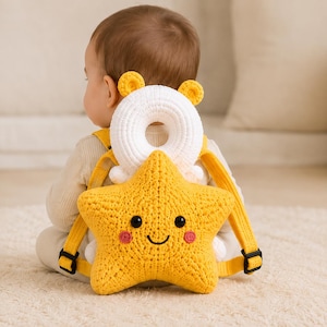May include: A yellow crocheted star-shaped head protector backpack with a white circular top piece featuring small yellow ears. The star has black embroidered eyes, a curved mouth, and pink circular cheeks, attached with yellow adjustable straps.