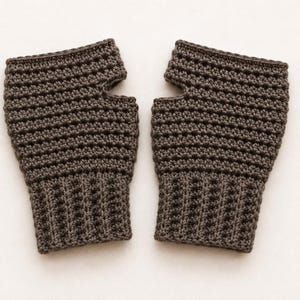 May include: A pair of dark brown fingerless gloves crafted with a textured crochet stitch. The gloves feature a ribbed cuff at the wrist and a distinct opening for the thumb, showcasing a consistent pattern throughout the dark brown yarn construction.
