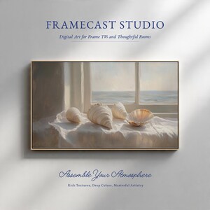 May include: A rectangular framed digital art print featuring four seashells resting on a white cloth surface in front of a window overlooking the ocean. The text FRAMECAST STUDIO, Digital Art for Frame TVs and Thoughtful Rooms, and Assemble Your Atmosphere, Rich Textures, Deep Colors, Masterful Artistry are visible.