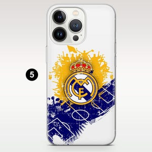 May include: A clear smartphone case featuring a Real Madrid logo with a crown, a yellow silhouette of cheering fans, and a blue soccer field diagram with a distressed, textured graphic design. The number 5 is visible on the left side.