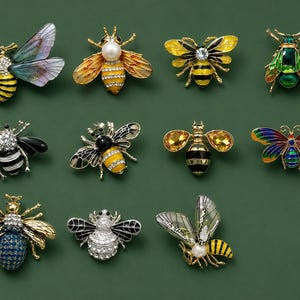 May include: A collection of eleven insect-shaped brooches featuring various designs including bees and beetles. The pins are crafted with gold-tone metal, colorful enamel, clear rhinestones, and faux pearls, showcasing diverse wing patterns and body textures.