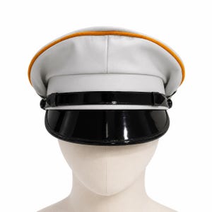 Op de afbeelding: Een witte militaire pet met een gladde afwerking, een feloranje bies langs de bovenkant en een glanzende zwarte lakleren klep. Een bijpassende zwarte lakleren kinband is bevestigd met twee kleine zwarte knopen aan de zijkanten van de pet.