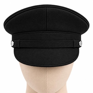 May include: A solid black military-style cap featuring a structured crown and a flat visor. A horizontal black strap runs across the front, secured on both sides by polished silver-tone metal buttons. The cap has a smooth, uniform texture.