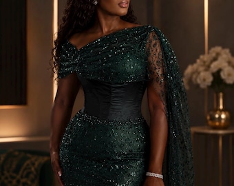 May include: A floor-length dark emerald green gown featuring a sequined bodice and skirt, a solid black satin corset-style waist, and a sheer, sequin-embellished cape sleeve. The garment is paired with a small, rectangular, metallic gold clutch.