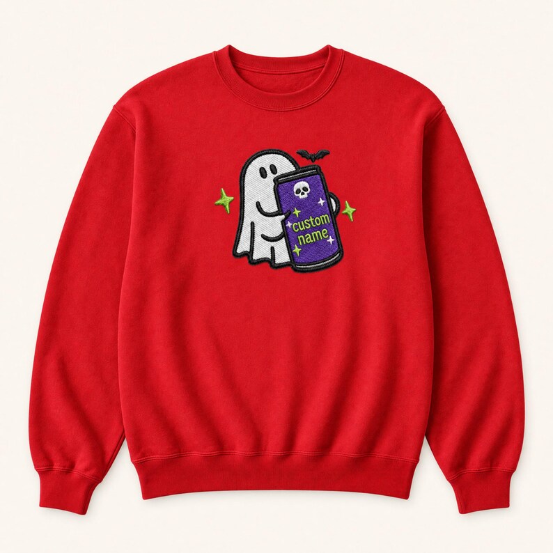 May include: A red crewneck sweatshirt featuring an embroidered design of a white ghost holding a purple can. The can displays a skull icon, the text "custom name" in green, and small star accents. A small black bat is positioned above the ghost.