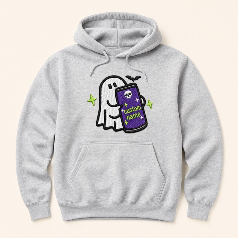 May include: A light grey hooded sweatshirt featuring an embroidered graphic of a white ghost holding a purple can with a skull icon and the text custom name. The design includes a small black bat and four lime green four-pointed stars.