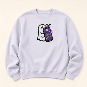 May include: A light purple crewneck sweatshirt featuring a central embroidered graphic of a white ghost holding a purple energy drink can. The can displays a small white skull icon, yellow star accents, and the text custom name in green.