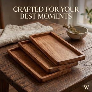 May include: Three rectangular wooden trays with raised edges stacked on top of each other. The text CRAFTED FOR YOUR BEST MOMENTS is displayed at the top. The trays have a natural wood grain finish and are positioned on a dark wooden surface.