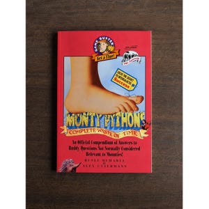 May include: A red book titled Monty Python's Complete Waste of Time, featuring a large foot illustration, a Game Buster logo, and the text Solve the Secret to Intergalactic Success. The cover includes the authors' names, Rusel Demaria and Alex Uttermann.